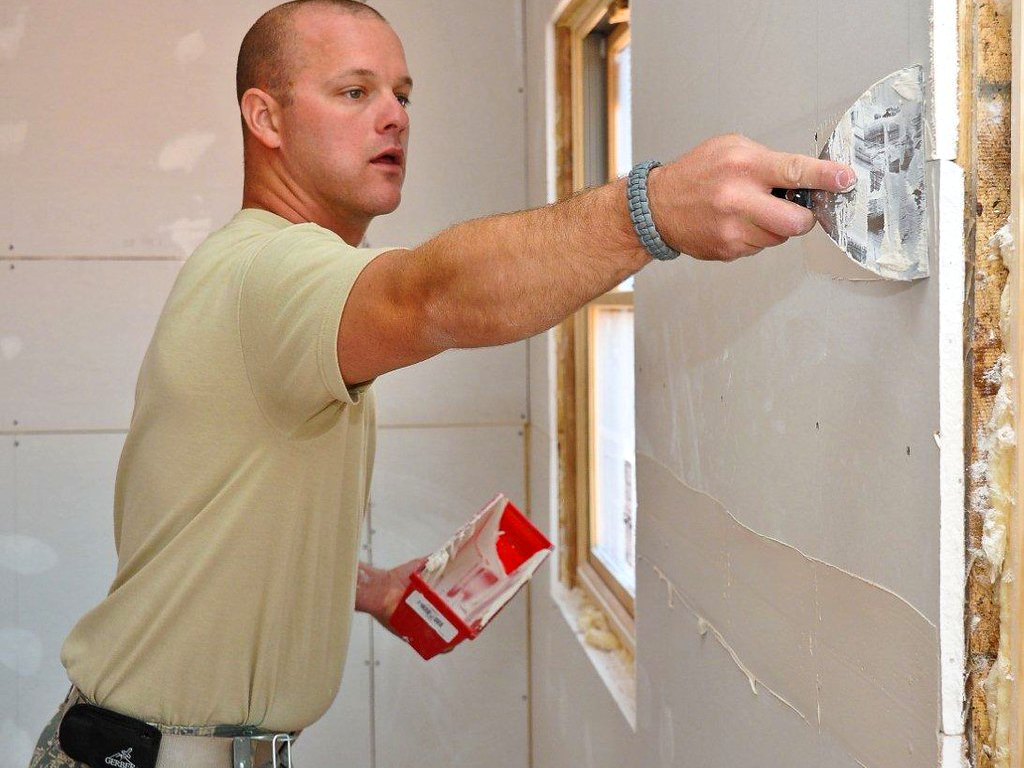 Craftsman finishing a wall repair with a taping knife